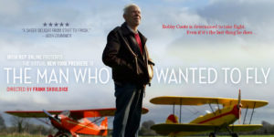 An elderly white Irish male, Bobby Coote, stands in a brown jacket and dark trousers against a blue sky with two small planes further away in the background: one yellow and one red. Irish Rep Online presents the virtual New York premiere of THE MAN WHO WANTED TO FLY directed by Frank Shouldice is centered. "Five stars - a sheer delight from start to finish," a quote from the Irish Examiner is located in the upper right corner. "Bobby Coote is determined to take flight. Even if it is the last thing he does..." is in the upper right corner.